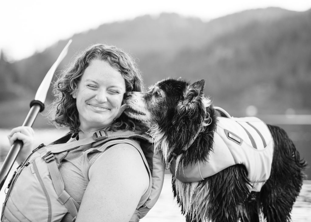 Dog kissing owner on kayak